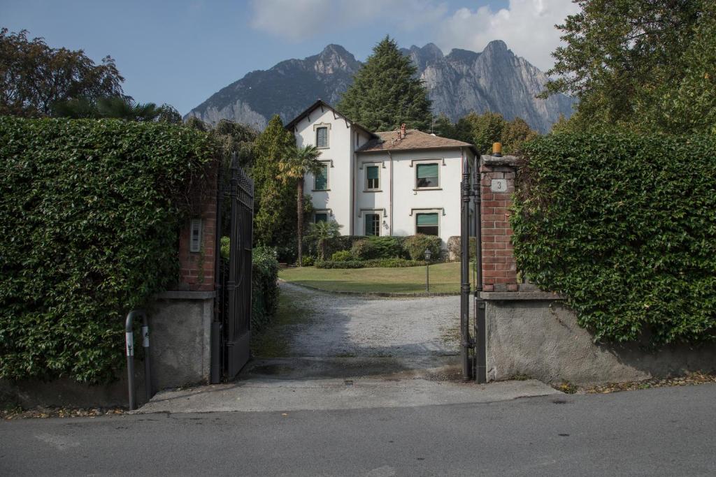 an open gate to a house with mountains in the background at Villa del Cigno in Lecco