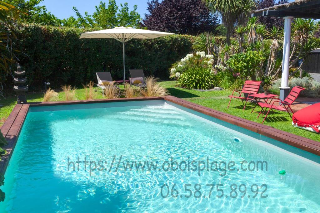 een zwembad in een tuin met stoelen en een parasol bij Chambres d'hôte Ô Bois Plage in Gujan-Mestras
