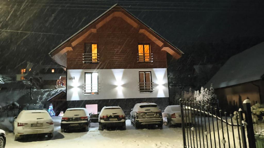 een huis met auto's buiten geparkeerd in de sneeuw bij Apartmánový Dom Terchová in Terchová