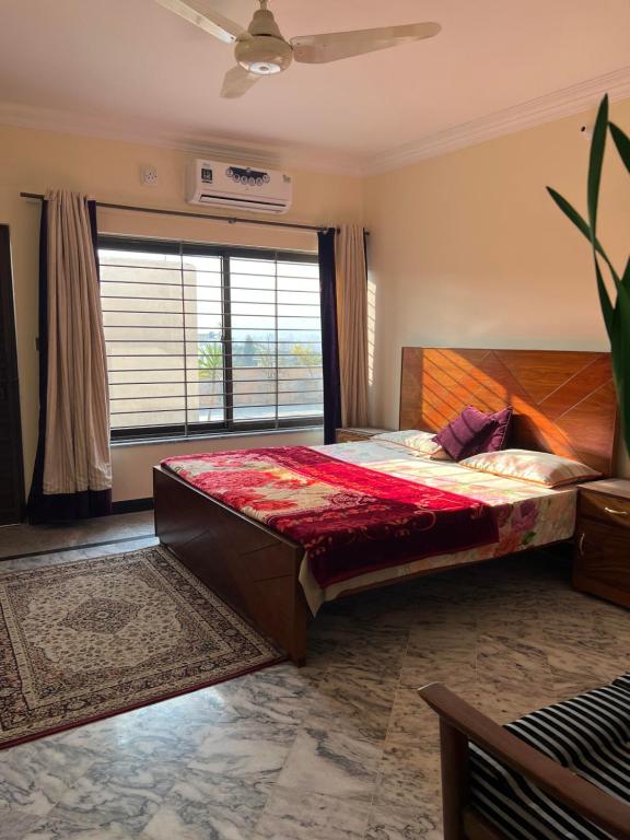 a bedroom with a large bed and a large window at Elysium Inn in Abbottabad