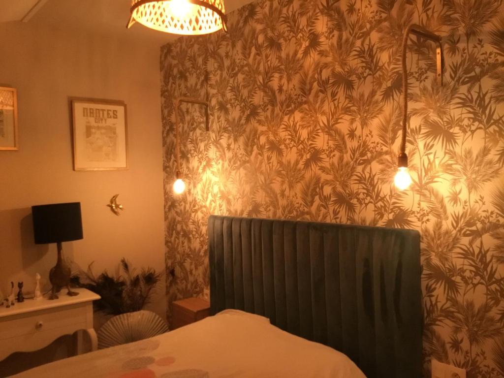a bedroom with a bed and a wall with a plant wallpaper at Chez David Tony in La Celle-sous-Gouzon