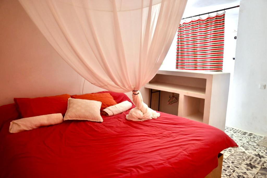 a bedroom with a red bed with a curtain at Dar-west in Demina