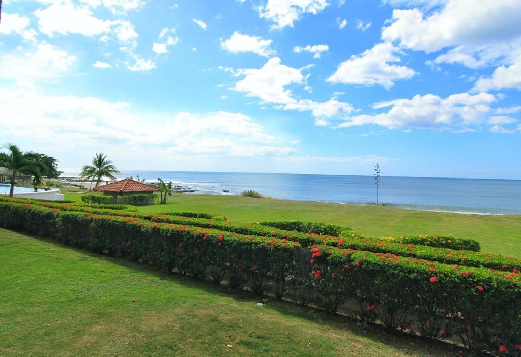 a garden with a hedge and flowers in front of the ocean at Suite Esteli 114 Gran Pacifica Resort in San Diego