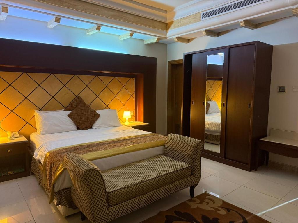a bedroom with a bed and a chair and a mirror at اجنحة الخزامى المخدومة in Yanbu