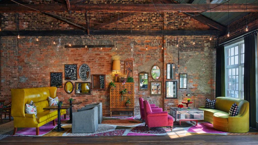 a living room with yellow and pink chairs and a brick wall at Hotel Abacus in Athens