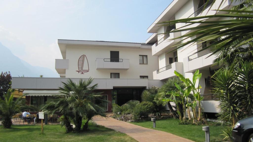 a building with palm trees in front of it at Hotel Villa Claudia in Nago-Torbole