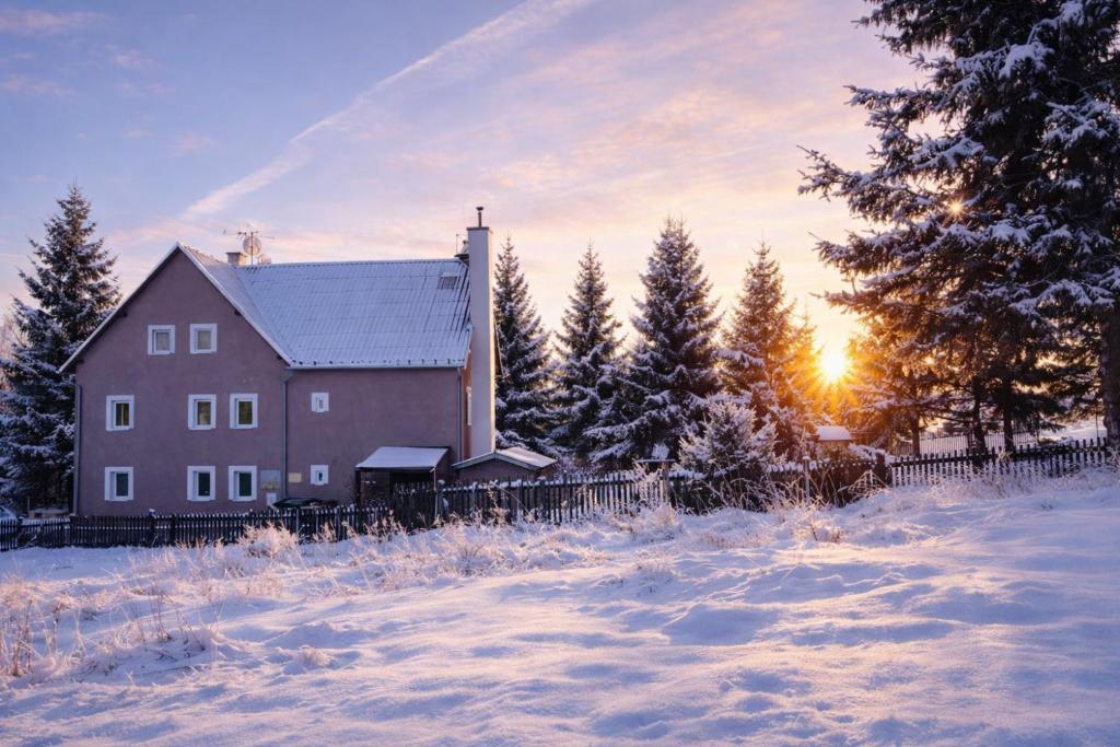 Een schuur in de sneeuw met de zon op de achtergrond. bij Forest House near Klínovec with 5 Independent Apartments in Kovářská