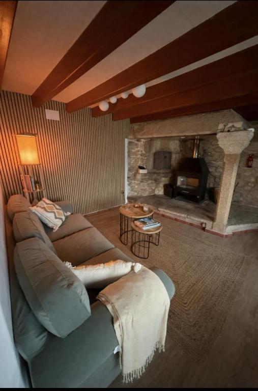 a living room with a couch and a stone fireplace at Casa Gure Amets - Costa da Morte in Cambeda