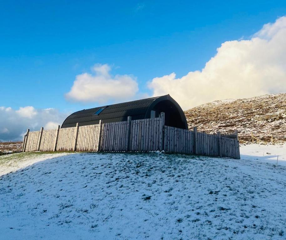 a wooden fence in the snow next to a building at Kelleys Pod in Berneray