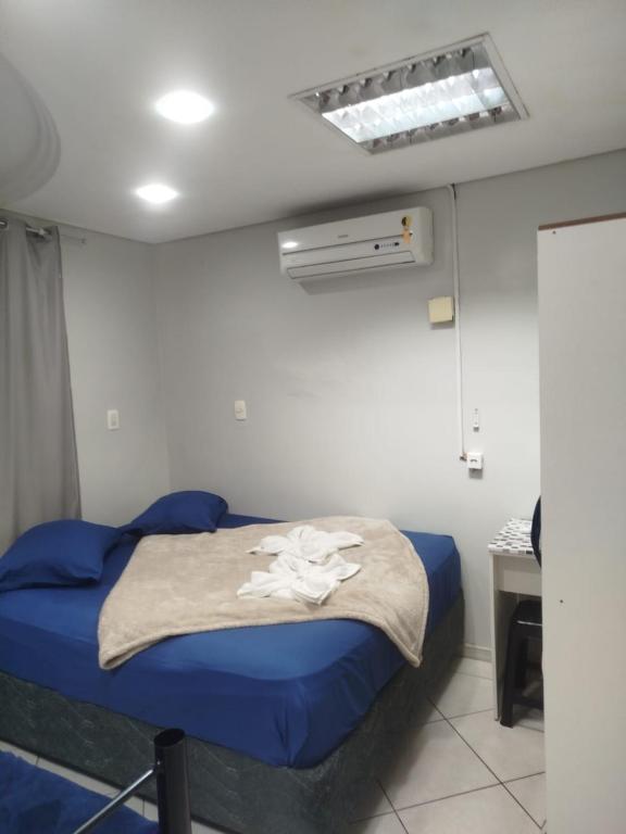 a bedroom with a blue bed with a white flower on it at Pousada Central Quarto 1 in Joinville