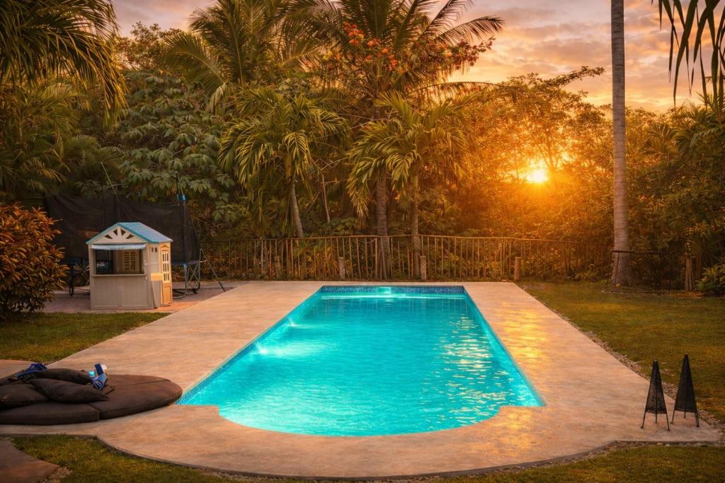 a swimming pool with a sunset in the background at Green Oasis private pool and cinema in Puerto Aventuras