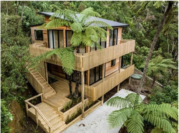a wooden house in the middle of a forest at Ponga House - Kaitoke Waters in Okupu