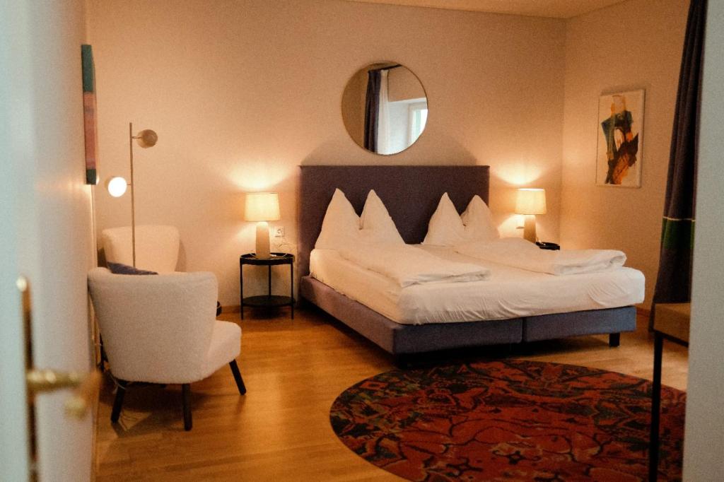 a bedroom with a bed and a chair and a mirror at Hotel Restaurant Der Greif in Leoben