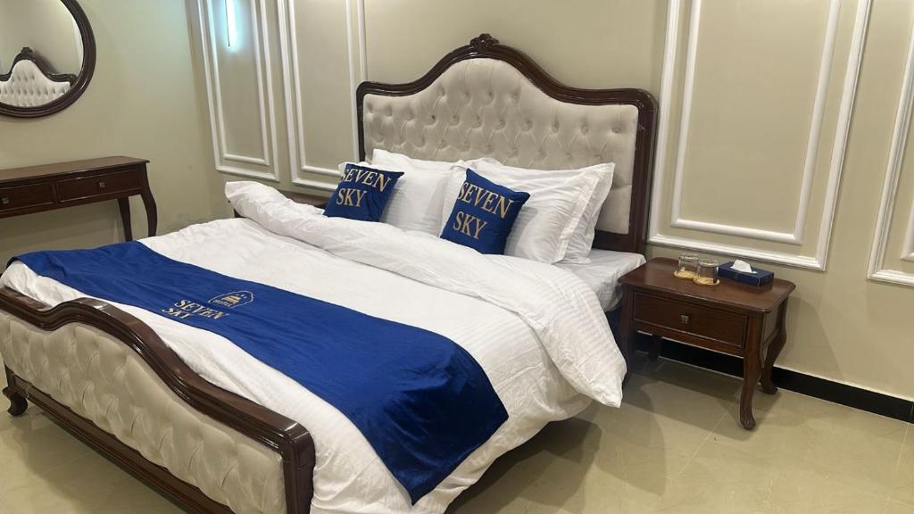 a large bed with blue and white sheets and pillows at Seven Sky Hotel in Murree