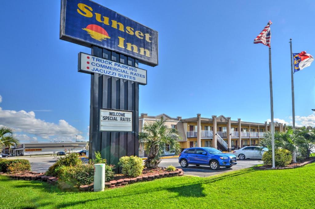 un panneau indiquant une auberge au coucher du soleil dans un parking dans l'établissement Sunset Inn, à Jacksonville