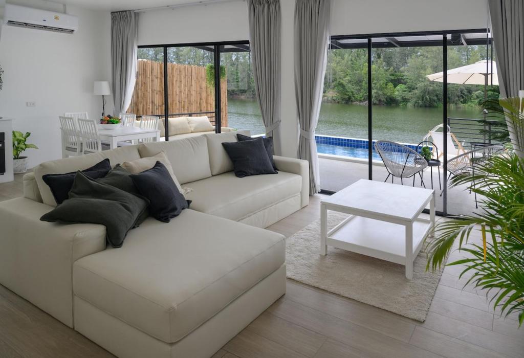 a living room with a white couch and a table at Zen Beach Lake Villa 3 - orchid villa in Haad Chao Phao