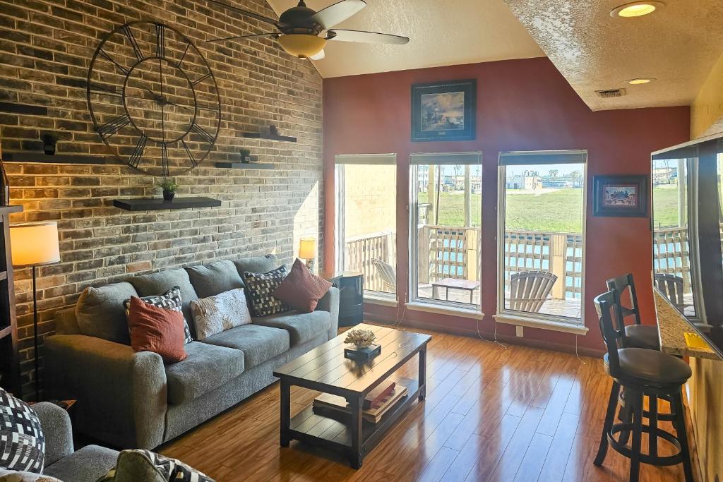 a living room with a couch and a brick wall at Boat Slip Access: North Padre Island Condo! in Padre Island