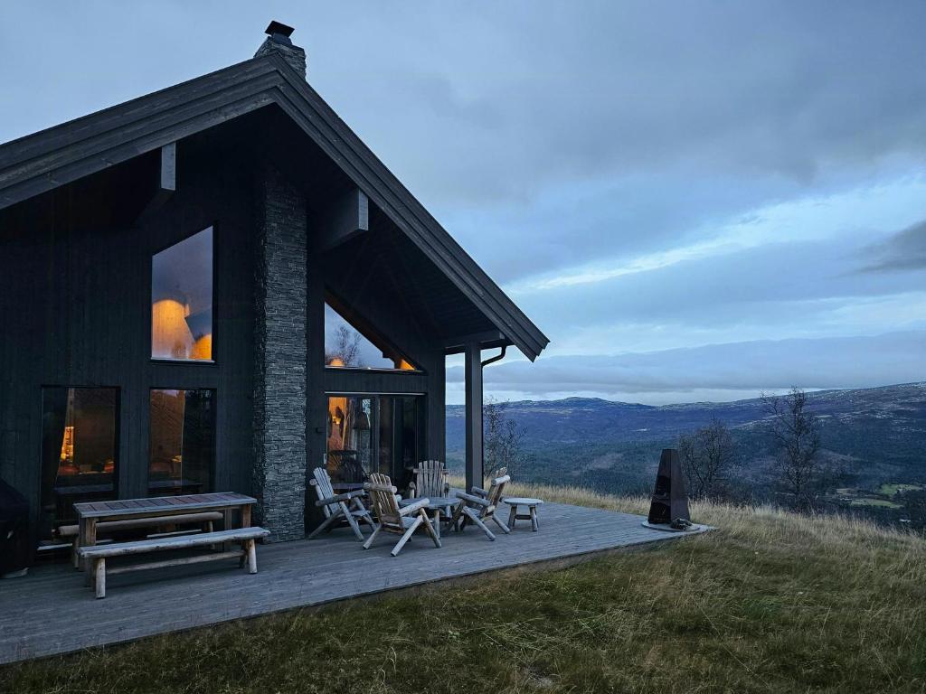 een blokhut met een tafel en stoelen op een terras bij Mountain Cabin With Panoramic Views In Oppdal in Gorset