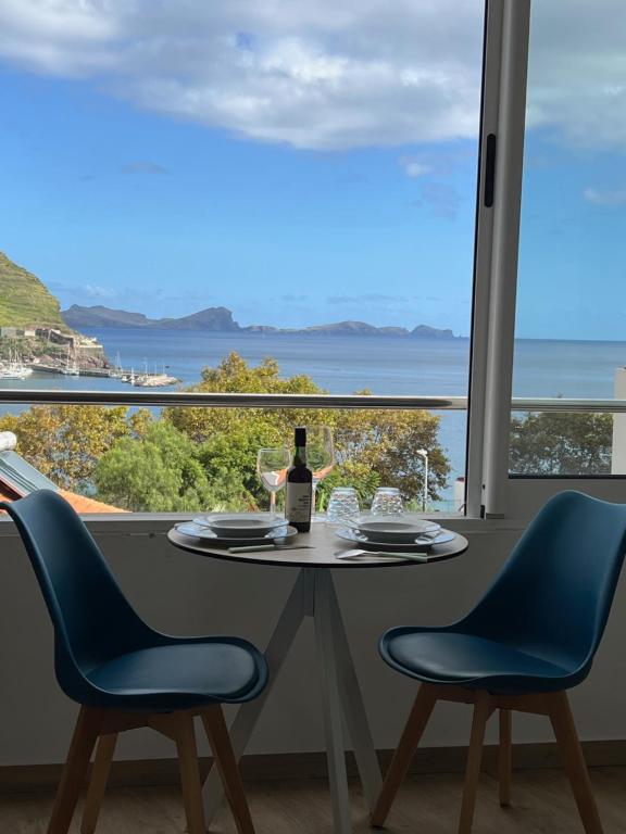 a table with a bottle of wine and two chairs at Feeling Like Home Machico in Machico