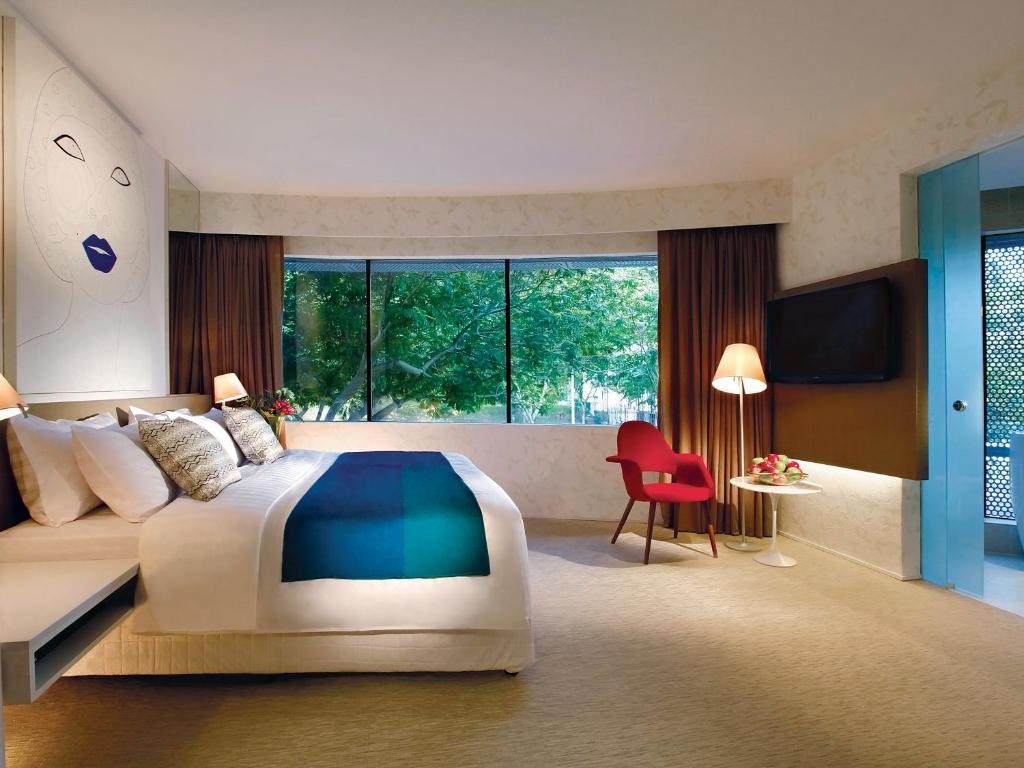 um quarto com uma cama grande e uma cadeira vermelha em D'Hotel Singapore managed by The Ascott Limited em Singapura