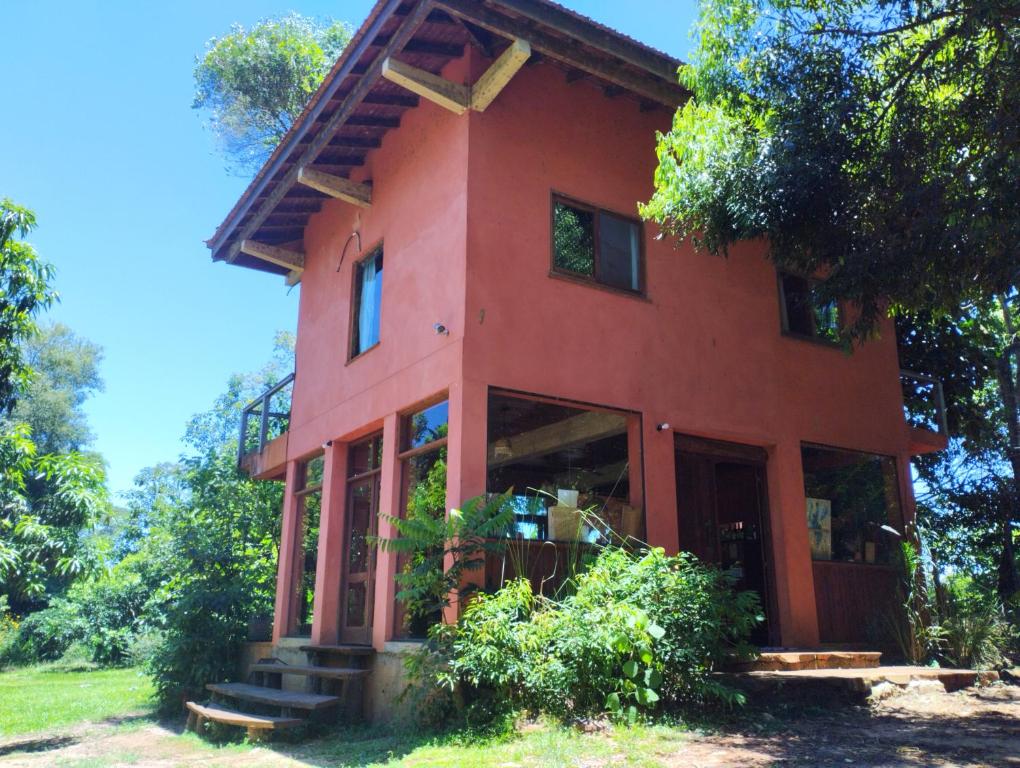 een rood huis met glazen deuren en bomen bij Nativa Iguazu in Puerto Iguazú