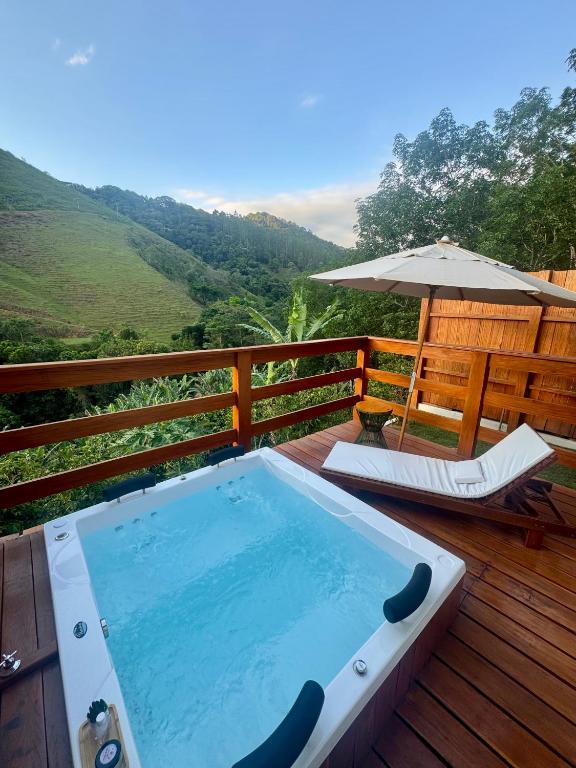 a hot tub on a wooden deck with an umbrella at Chalés Bermond- Rota da Ferradura in Guarapari