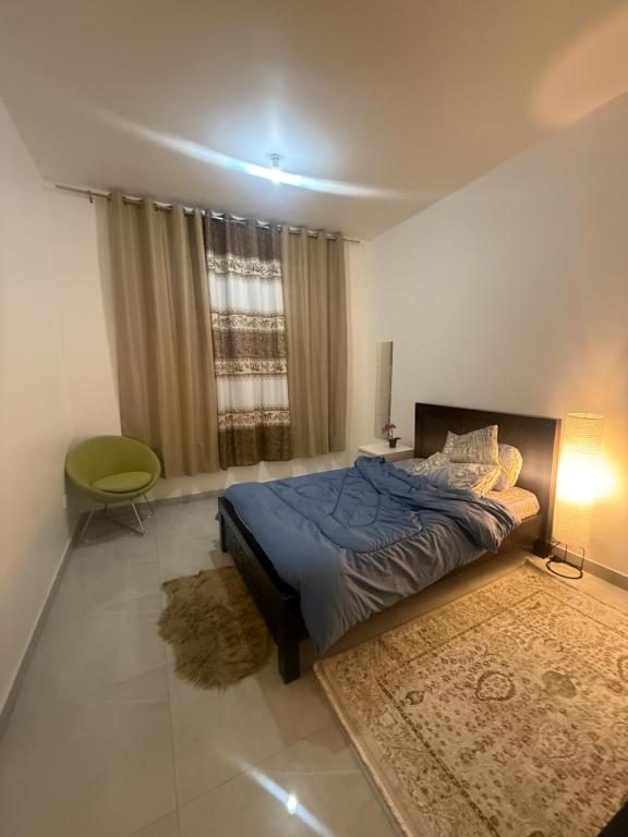 a bedroom with a blue bed and a green chair at Vi Home Stay Corniche in Abu Dhabi