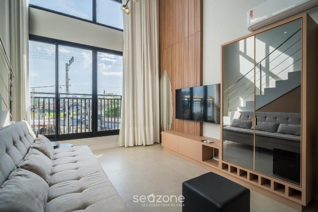 a living room with a couch and a large television at Full Loft 290 m from the Beach CPH0202 in Florianópolis