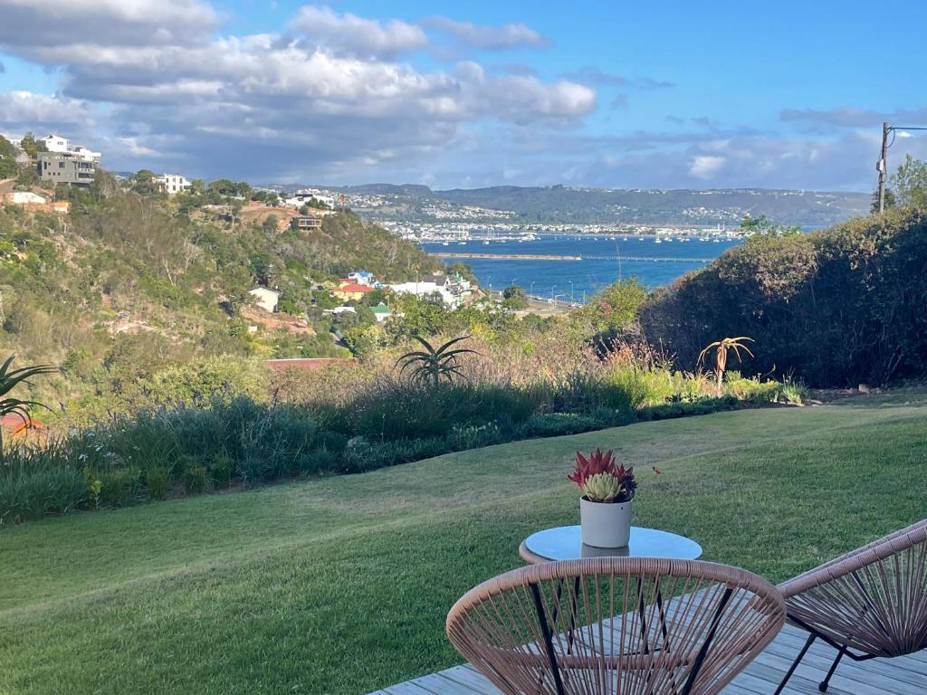 a table and two chairs on a patio with a view of the water at Knysna Estate Lagoon - Garden Apartments- Secure Estate - off the grid in Knysna