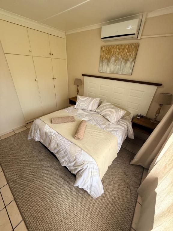 a bedroom with a large bed with white sheets at Aloha Sands Scottburgh in Scottburgh