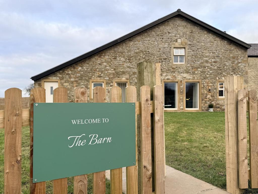 a sign on a fence in front of a stone house at The Barn in Skipton