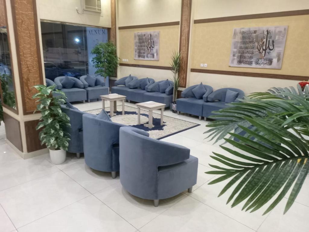 a waiting room with blue couches and plants at ركن فينيسيا للشقق المخدومة in Hail