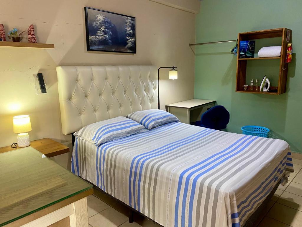 a bedroom with a bed with a blue and white striped blanket at Mini Suite Apartamento in San Pedro Sula
