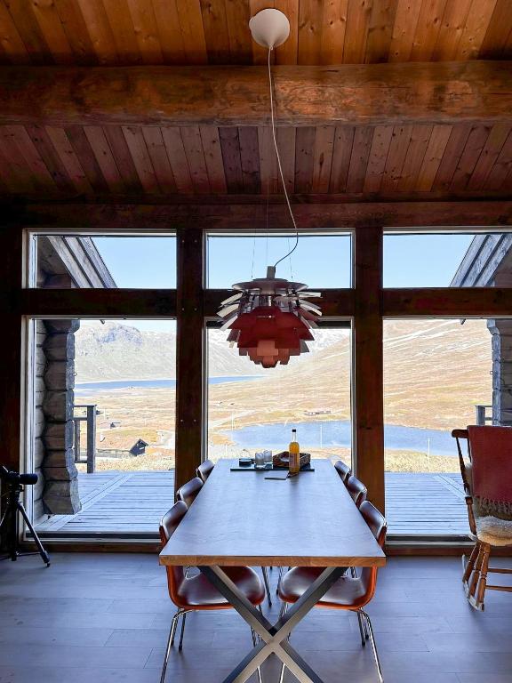 a dining room with a table and a large window at Spectacular Cabin With View In Jotunheimen in Eidsbugarden