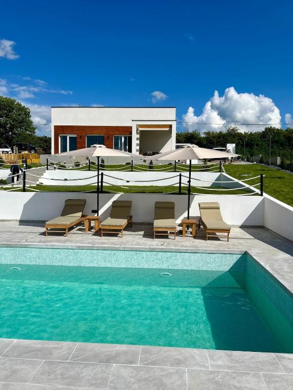 a swimming pool with chairs and a house at Casa Toleni in Ba°evac
