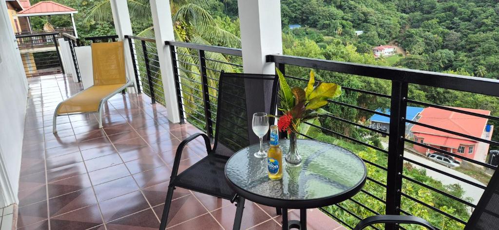 a balcony with a table with glasses and flowers on it at Villas De Morne in Castries