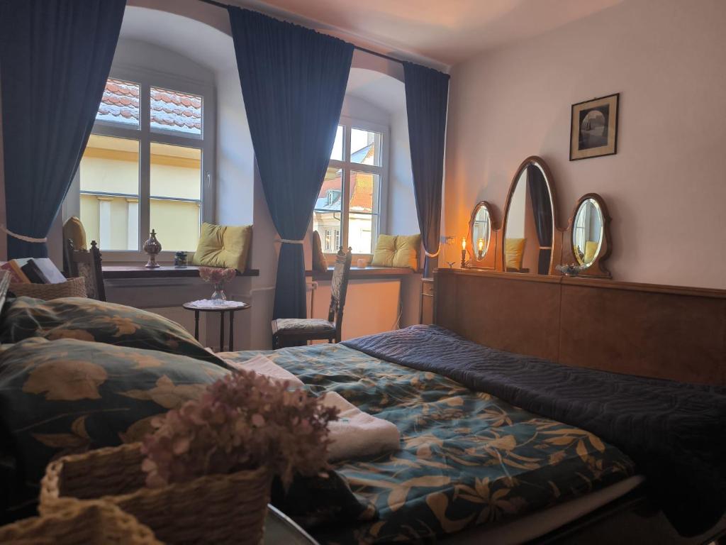 a bedroom with a bed with blue curtains and mirrors at Neo Retro in Jelenia Góra