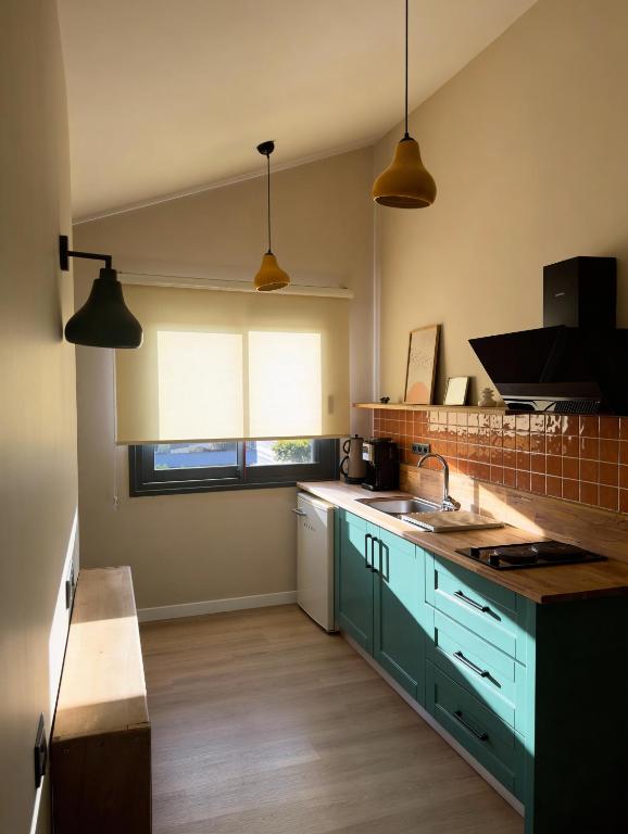 a kitchen with green cabinets and a sink and two lights at InOut Social in Fethiye