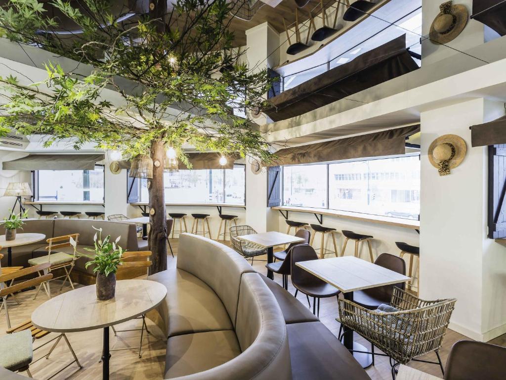 un ristorante con tavoli, sedie e un albero di Ibis Styles Lisboa Centro Marquês de Pombal a Lisbona