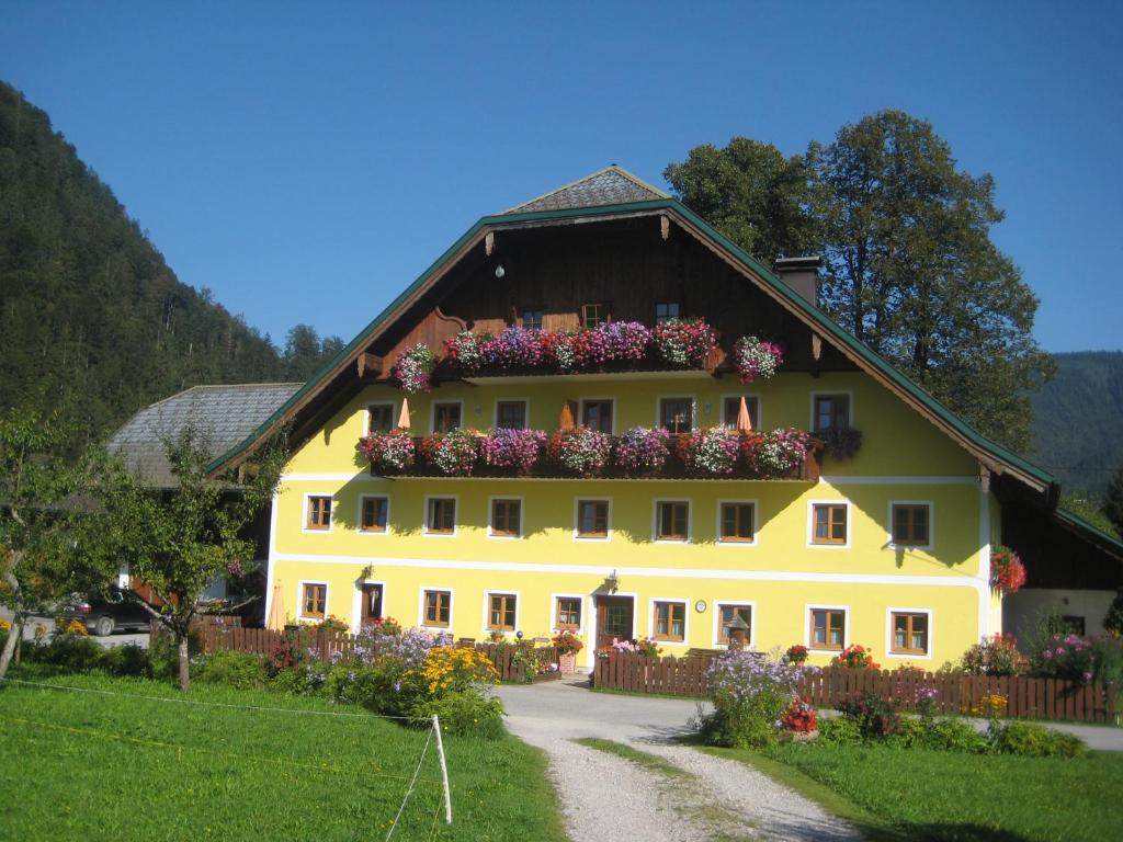 a large yellow house with flower boxes on it at Biobauernhof Hauserbauer in Hintersee