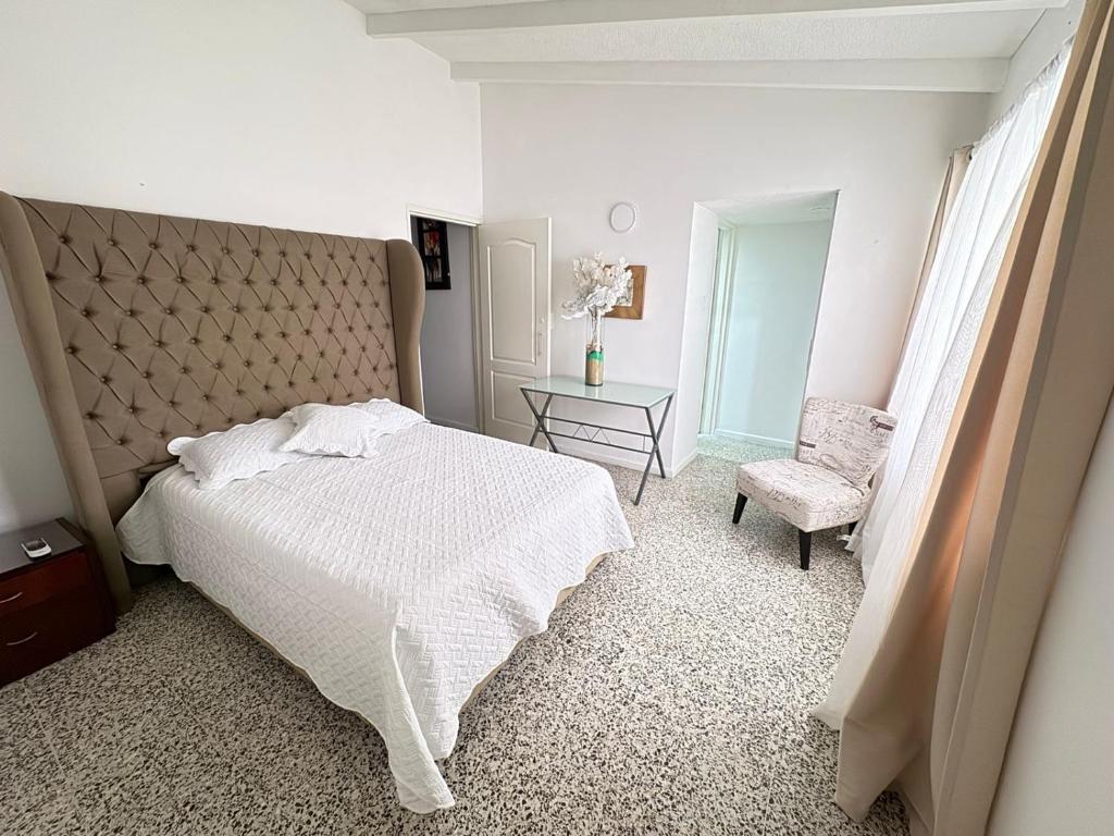 a bedroom with a white bed and a chair at Casa Lucy Alojamientos in Palmira