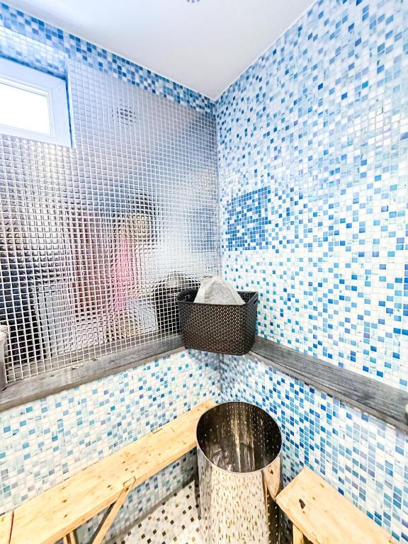 a bathroom with blue tiled walls and a trash can at Anetes pirts in Jaunanna