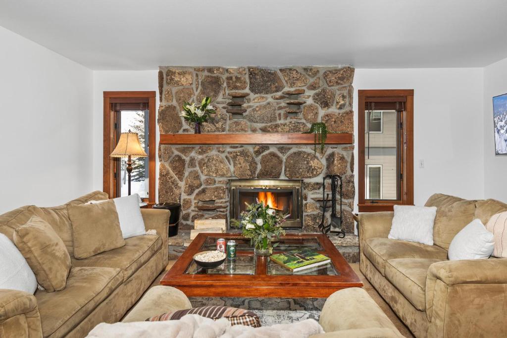 a living room with couches and a stone fireplace at Abode at Sundance in Teton Village