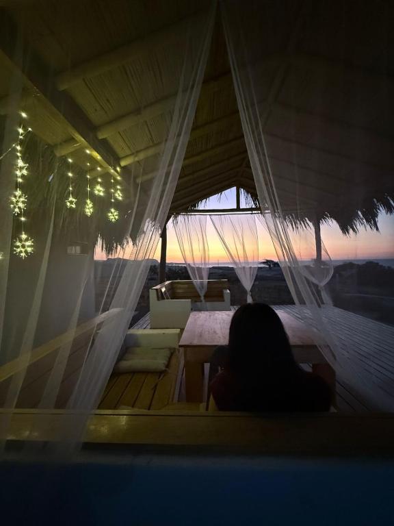 a woman sitting at a table in a tent at Casa Vichayito - Los Órganos in Los Órganos