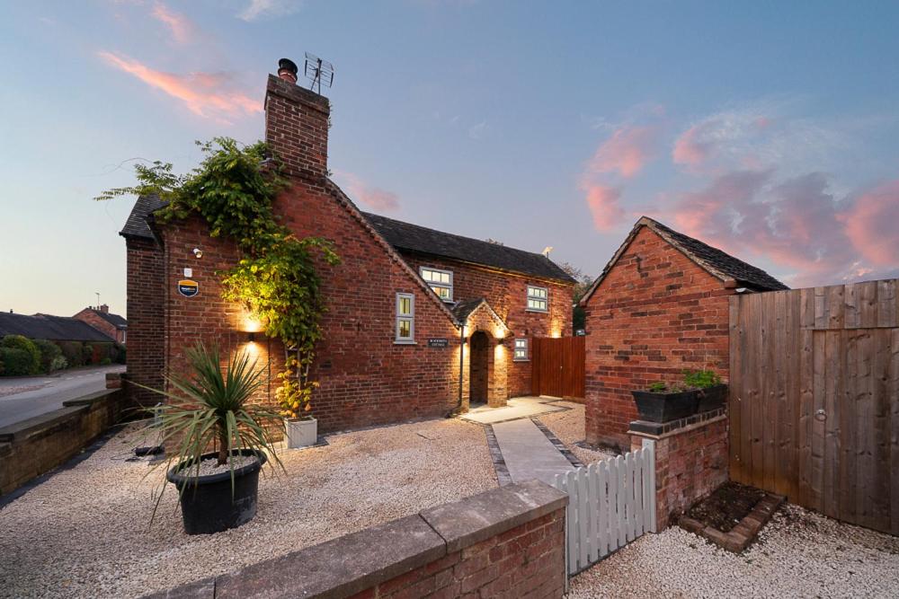 an old brick house with a fence and a house at Blacksmiths Cottage by Birch Stays in Needwood