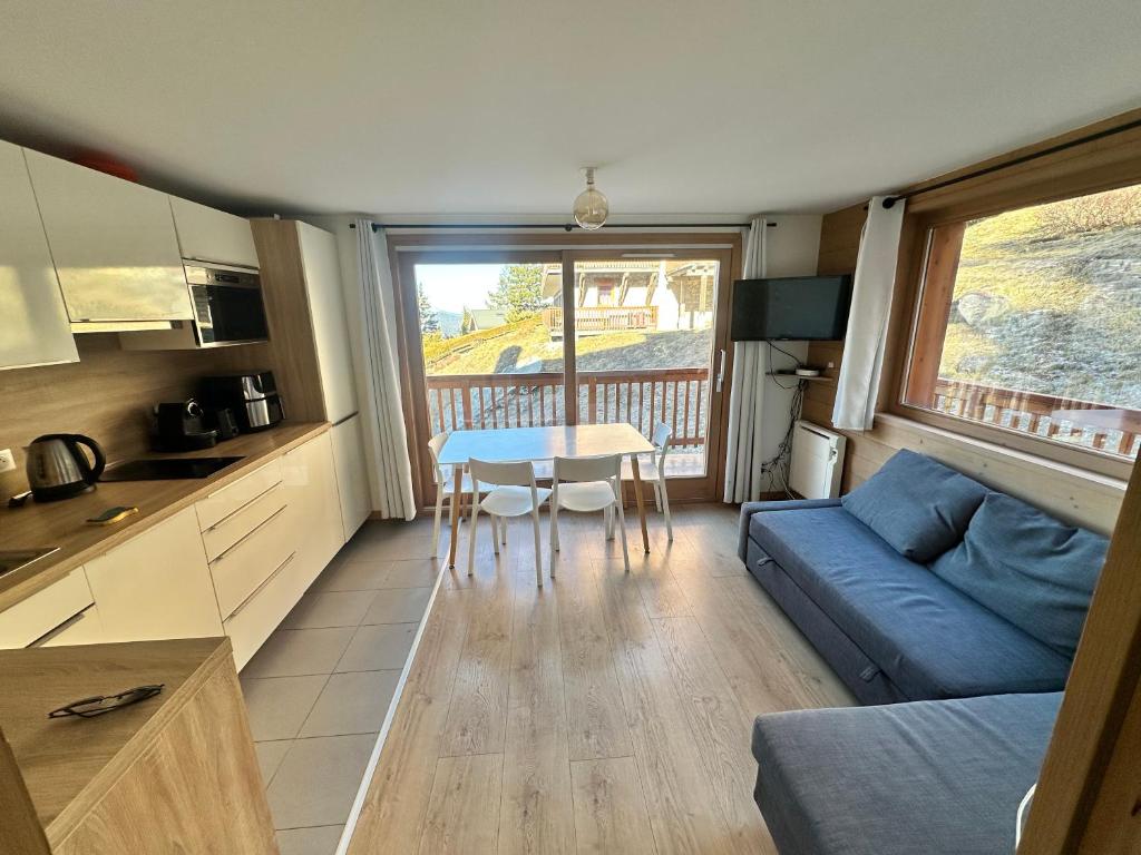 un soggiorno con un divano blu e un tavolo di Méribel 2 pièces avec cabine, centre, proche commerce et pistes avec parking et wifi état neuf a Les Allues