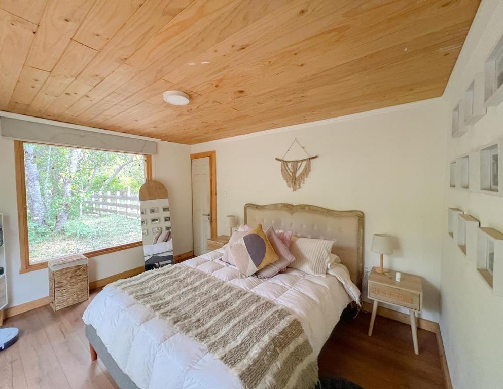 a bedroom with a large bed with a wooden ceiling at Cabaña de Montaña con Río in Puhala