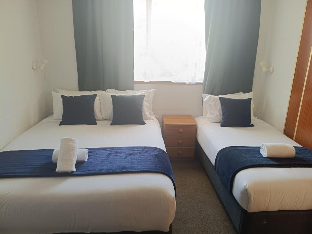 two beds in a small room with blue and white at Cumberland Motel in Dunedin