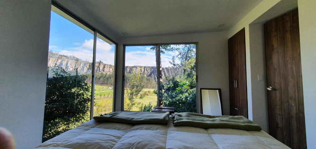 a bedroom with a bed and a large window at Casa del Bosque in Suesca