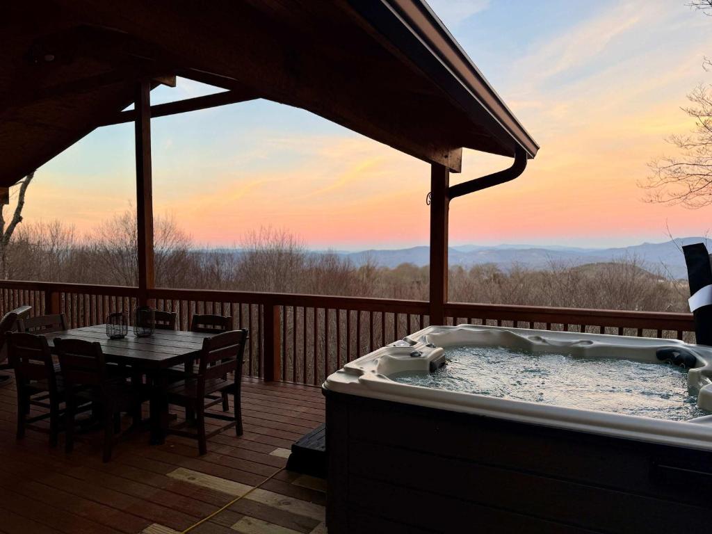 a hot tub on a deck with a table and chairs at Paws at the Peak in Beech Mountain